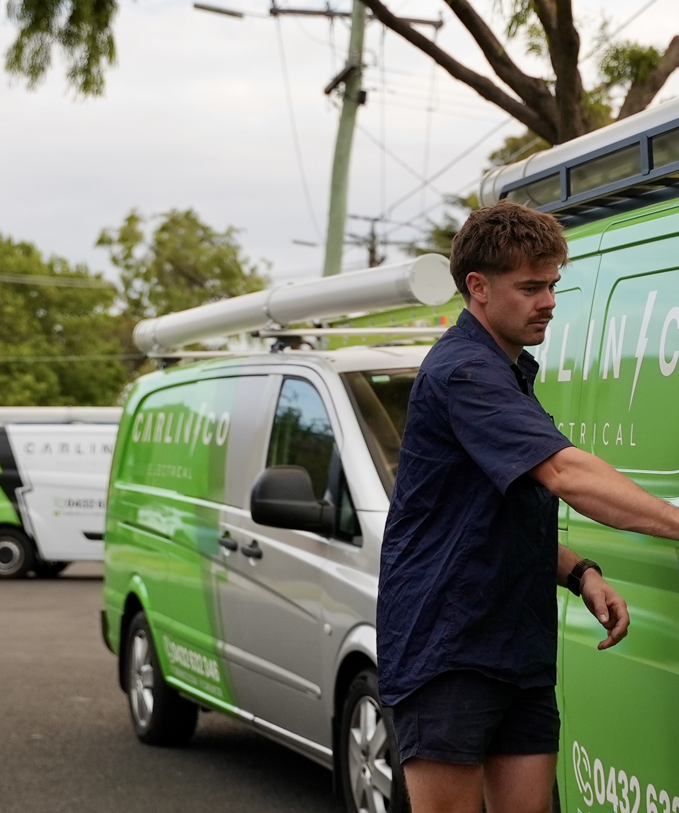 Carlin Co electrician standing by branded service vehicles in Melbourne