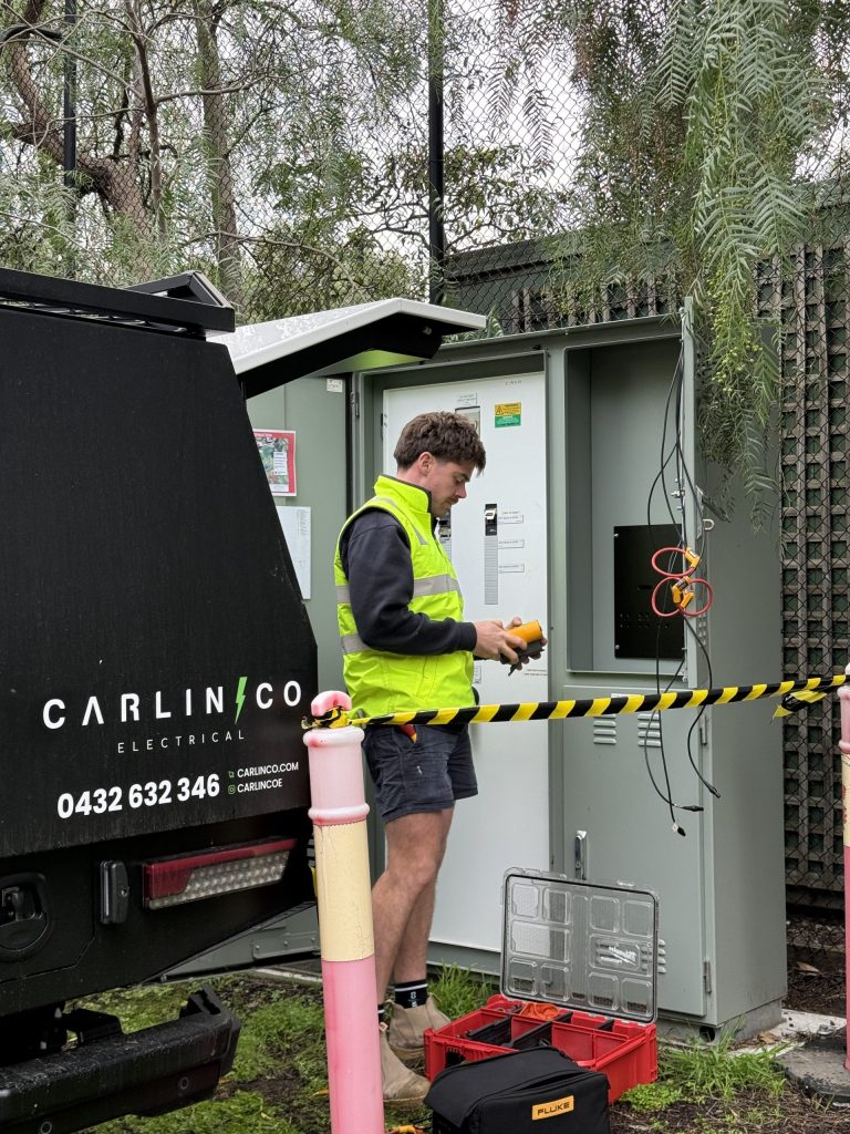 Carlin Co Electrical van branding visible with electrician working at commercial switchboard in Melbourne