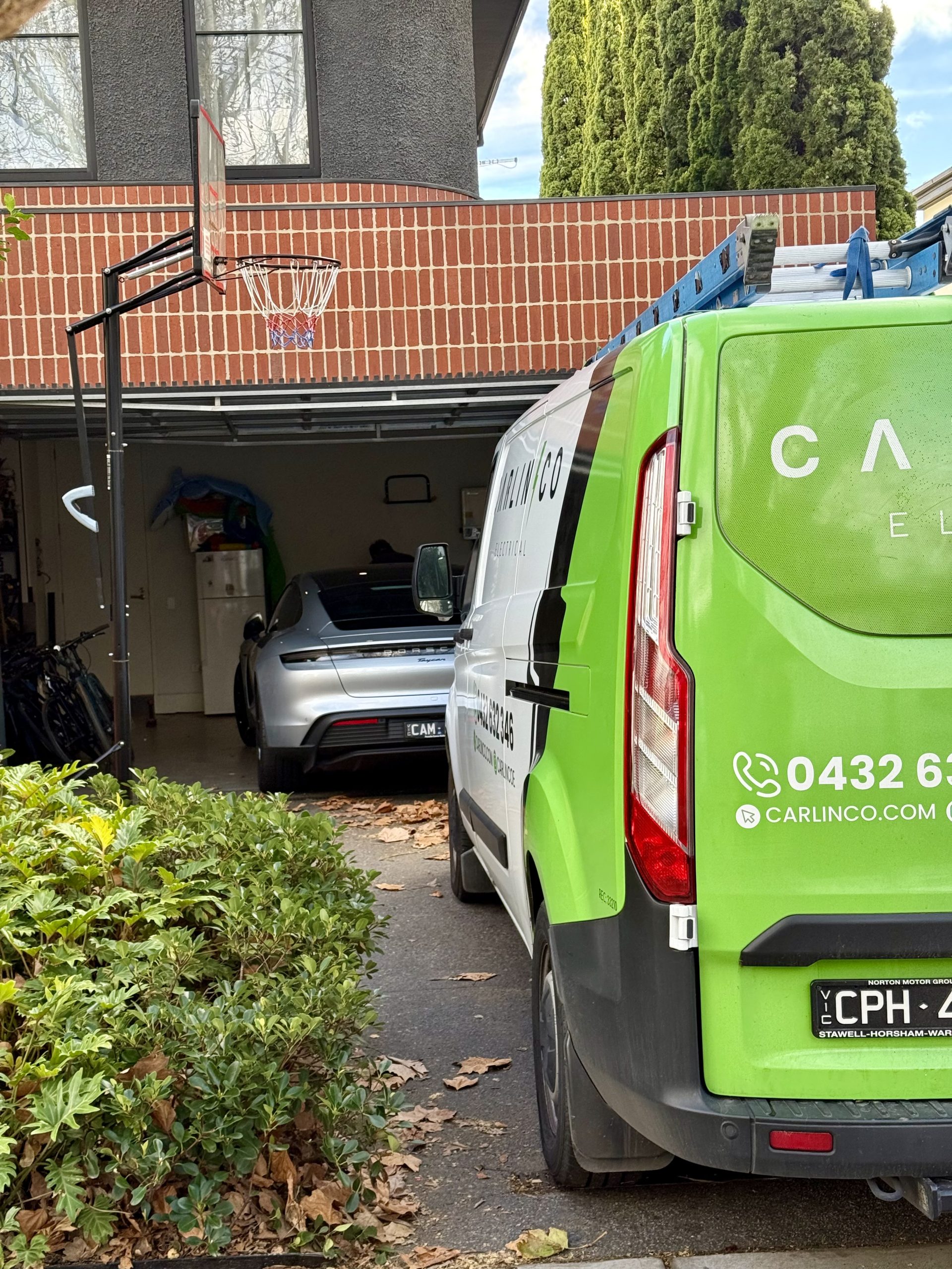 Carlin Co Electrical service vehicles at EV charger installation with Porsche Taycan