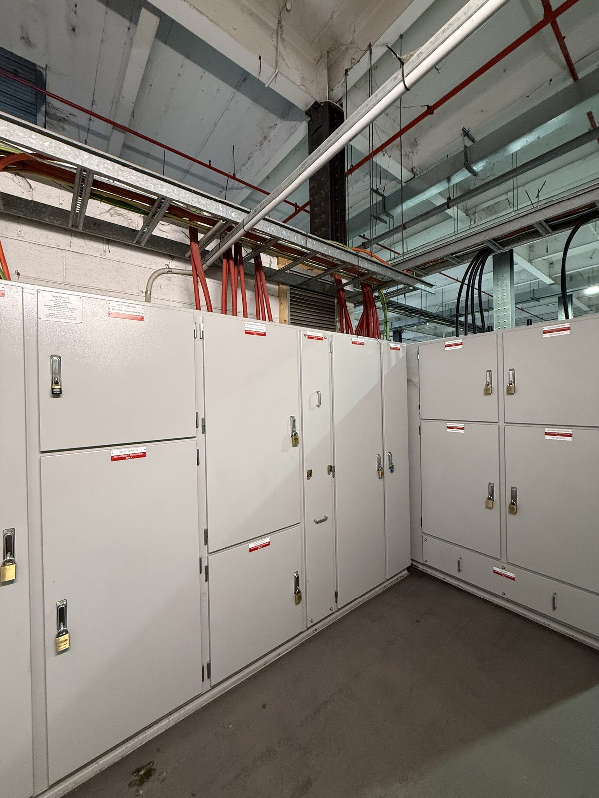 Large commercial main switchboard room with multiple panels and cable trays by Carlin Co Electrical